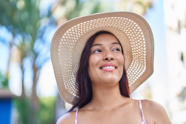Νεαρή όμορφη Ισπανίδα τουρίστρια χαμογελά με αυτοπεποίθηση κοιτάζοντας προς την πλευρά του δρόμου - Φωτογραφία, εικόνα