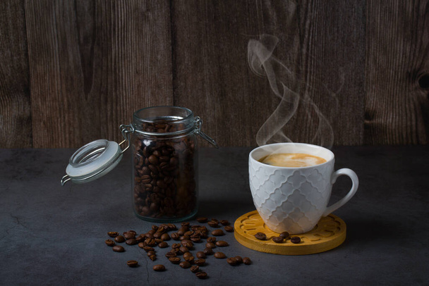 コピースペース付きの白いエスプレッソカップとコーヒー豆ダークテーブルの背景。アラビカ穀物,コーヒーショップ,カフェイン,ローストコンセプト - 写真・画像
