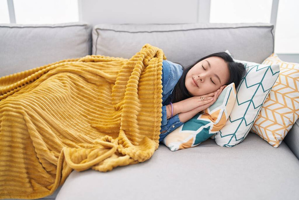 Young chinese woman lying on sofa sleeping at home - Photo, Image