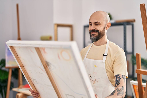 Mladý plešatý muž umělec se usmívá sebevědomě vypadající remíza na výtvarné studio - Fotografie, Obrázek