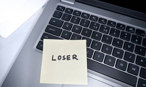 Loser написаний на блокноті, вставленому на ноутбук пов'язаного корпоративного життя
. - Фото, зображення