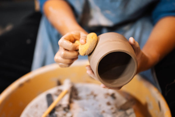 Közelkép a ügyes kéz készítés és szobrászat fazekas edény fazekas kerék szerszámok és víz műhelyben, Kreatív és műalkotás, Kézzel készített kézműves - Fotó, kép