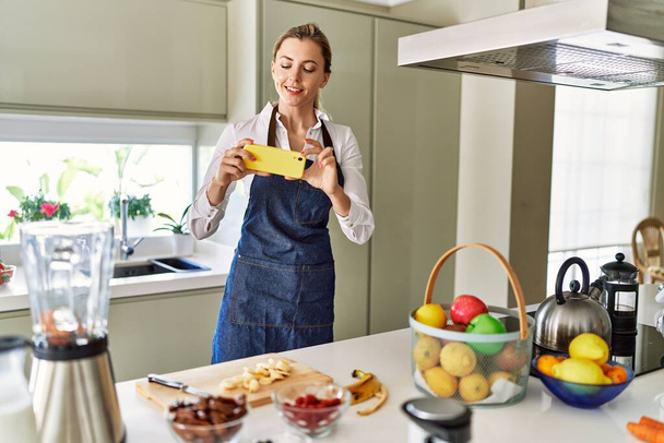 Young blonde woman make photo tu banana slices at kitchen - 写真・画像
