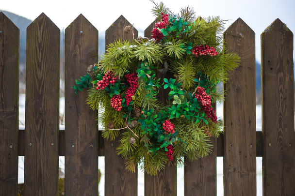 Couronne de Noël avec des baies rouges suspendues sur une clôture en bois
 - Photo, image