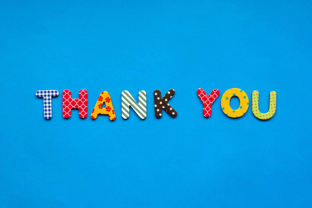 text thank you from bright colored paper letters on blue paper background - Photo, Image
