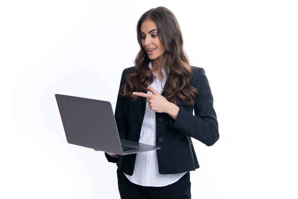 Portrait of a cheerful young casual girl standing isolated over gray background, using laptop computer. Business woman at work - Foto, Imagem