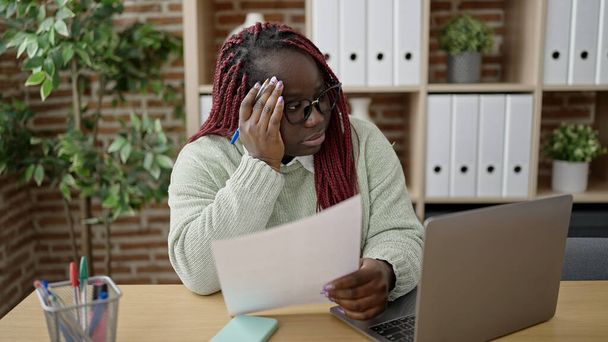 Afrikai nő fonott hajjal olvasási dokumentum szenved fejfájás az irodában - Fotó, kép