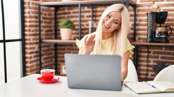 Blanke vrouw doet videogesprek met laptop kijken positief en gelukkig staan en glimlachen met een zelfverzekerde glimlach tonen tanden  - Foto, afbeelding