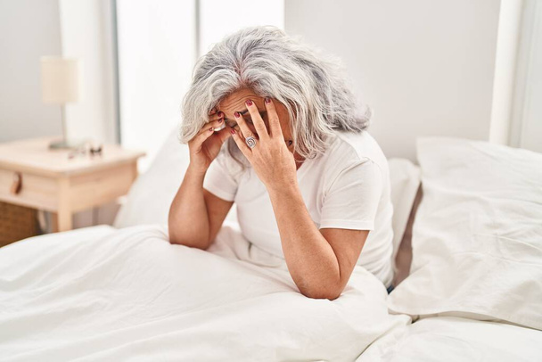 Mulher de meia idade estressado sentado na cama no quarto - Foto, Imagem
