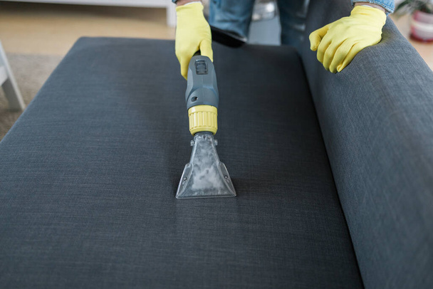 Man cleaning couch with washing vacuum cleaner - Foto, imagen