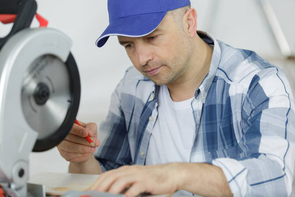 ein junger männlicher Bautischler mit moderner Kreissäge - Foto, Bild
