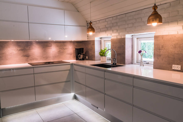 Сучасна міні-кухня з білою стільницею, чорна раковина і мідні металеві лампи, індустріальний стиль
 - Фото, зображення