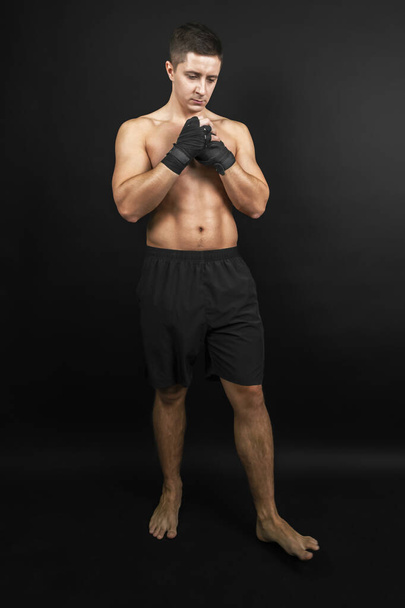 Boxer przygotował się do sparingu. Zdjęcie umięśnionego mężczyzny odizolowanego na czarnym tle. Siła i motywacja. - Zdjęcie, obraz