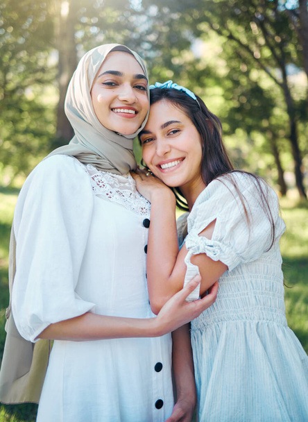 Kobiety szczęśliwe w ogrodzie, park leśny z drzewami i piknik ogrodowy na świeżym powietrzu w wielokulturowym letnim stylu. Portret przyjaciółki razem, muzułmanka w islamskim hidżabskim szaliku uśmiech i uścisk przyjaciela. - Zdjęcie, obraz