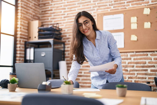 Young hispanic girl business worker writing on document working at office - Photo, image