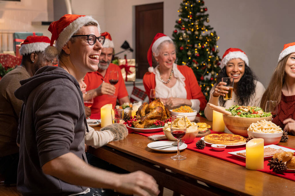 メリークリスマス、家族の両親と赤い帽子の子供の肖像、自宅でクリスマスの日を祝うダイニングルームでダイナーパーティーで楽しむ幸せな家族 - 写真・画像