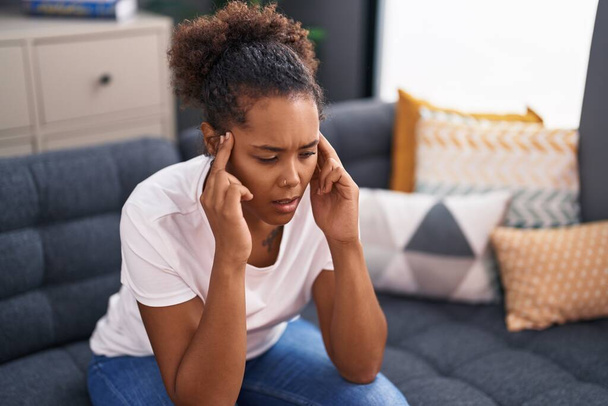 African american woman suffering for headache sitting on sofa at home - Fotó, kép