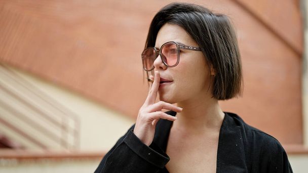 Молода біла жінка в сонцезахисних окулярах курить на вулиці - Фото, зображення