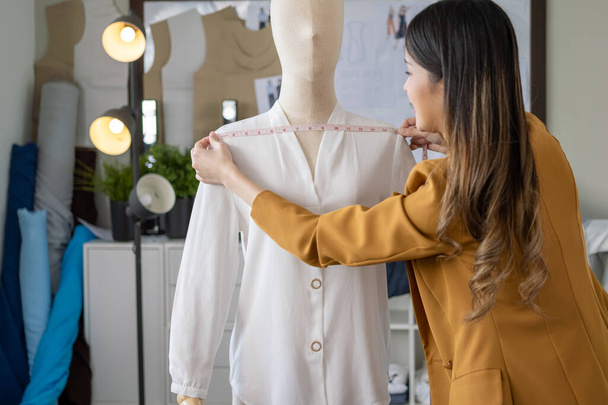 Happy female dressmaker cutting fabric on sketch line, Fashion designer stylist designing new clothes collection working in the fashion studio, Clothes business owner concept - 写真・画像
