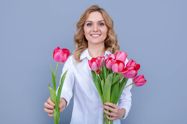 happy blonde woman with spring tulip flowers on grey background. - Foto, Imagem