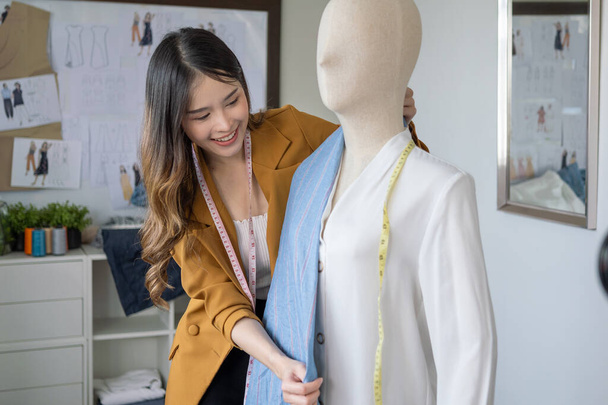Happy female dressmaker cutting fabric on sketch line, Fashion designer stylist designing new clothes collection working in the fashion studio, Clothes business owner concept - Foto, imagen