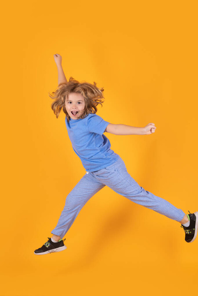 Funny boy jumping. Little child jumping over a yellow background - Φωτογραφία, εικόνα