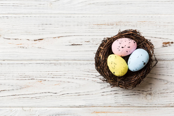 Colorful easter eggs in nest on table background with copy space top view. - 写真・画像