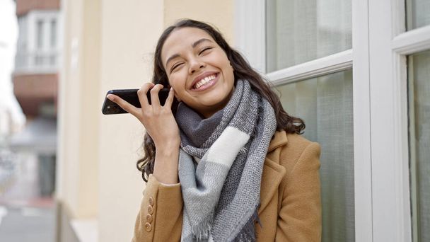 Young beautiful hispanic woman listening to voice message at street - Photo, Image