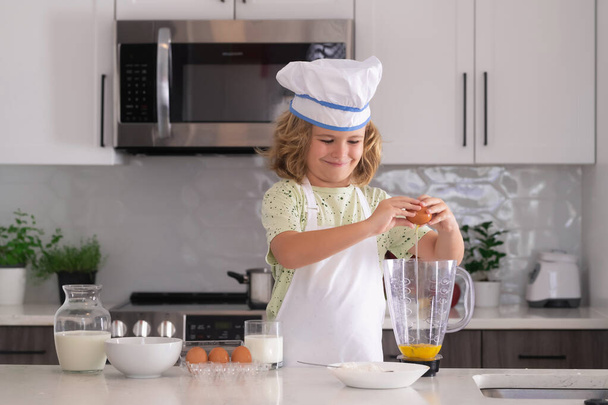 Kinderkoch kochen Kochkunst. Kinder kochen. Junge mit Schürze und Kochmütze bereitet in der Küche eine gesunde Mahlzeit zu. Kochprozess - Foto, Bild