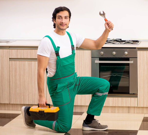Mladý dodavatel opravuje pec v kuchyni - Fotografie, Obrázek