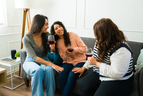 Onnellisia parhaita ystäviä, joilla on hauskaa nauraa juodessaan viiniä yhdessä rentoutuen olohuoneessa kotona - Valokuva, kuva