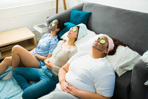 20 'li yaşlardaki genç kadınlar ve en iyi arkadaşlar yüz maskeleri ve cilt bakım ürünleri kullanarak yatıya kalıyorlar. - Fotoğraf, Görsel