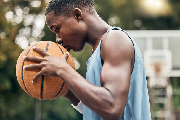 Sports, fitness and man with a kiss to a basketball in training, workout and athletic exercise outdoors. Culture, wellness and young player or athlete with passion and love for playing on court. - 写真・画像