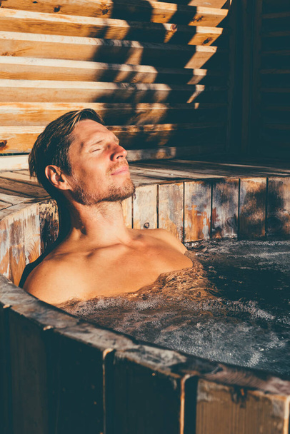 Άνδρας χαλαρώνοντας σε ξύλινο υδρομασάζ εξωτερική. . Υψηλής ποιότητας φωτογραφία - Φωτογραφία, εικόνα