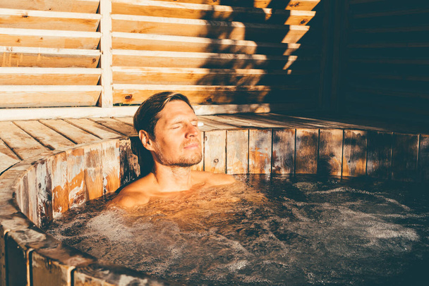 Man relaxing in wooden hot tub outdoor. . High quality photo - Valokuva, kuva