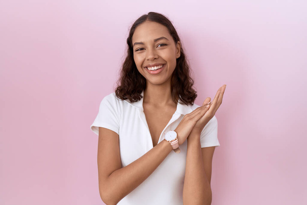 Young hispanic woman wearing casual white t shirt clapping and applauding happy and joyful, smiling proud hands together  - Φωτογραφία, εικόνα