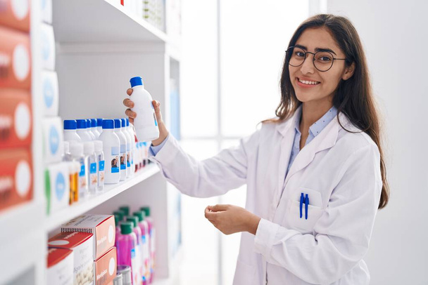 Молодая латиноамериканка-фармацевт организует полки в аптеке - Фото, изображение