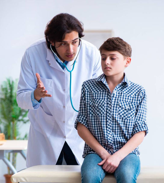 Врач-мужчина осматривает мальчика по стетоскопу
 - Фото, изображение