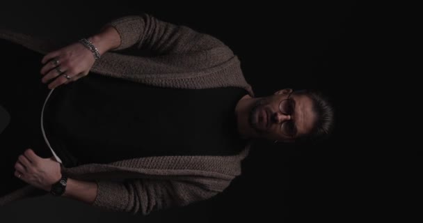 Dramatischer lässiger Mann reibt sich den Hals, fixiert Strickjacke und blickt mit stechendem Blick in die Kamera - Filmmaterial, Video
