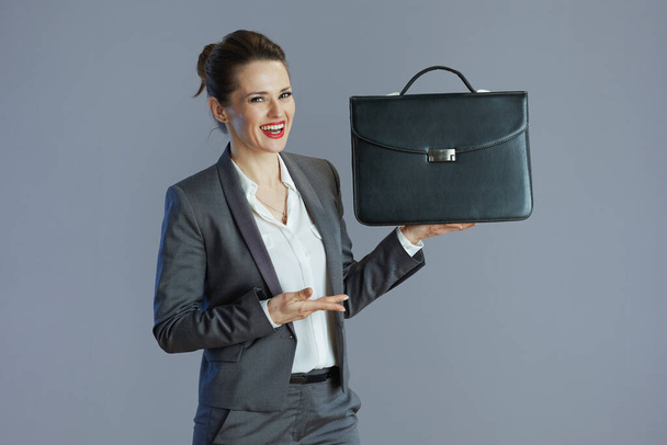 happy elegant woman worker in gray suit with briefcase isolated on gray. - Zdjęcie, obraz