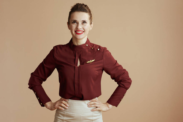 smiling elegant female stewardess isolated on beige background looking up at copy space. - Photo, image