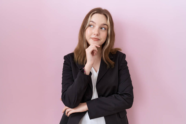 Young caucasian business woman wearing black jacket looking confident at the camera smiling with crossed arms and hand raised on chin. thinking positive.  - Foto, Imagem