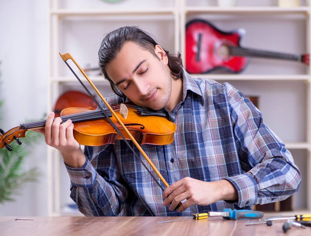 Молодий красивий ремонтант ремонтує скрипку
 - Фото, зображення