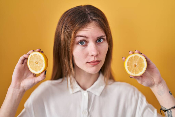 Красивая женщина держит лимоны скептически и нервно, хмурясь расстроен из-за проблемы. отрицательный человек.  - Фото, изображение