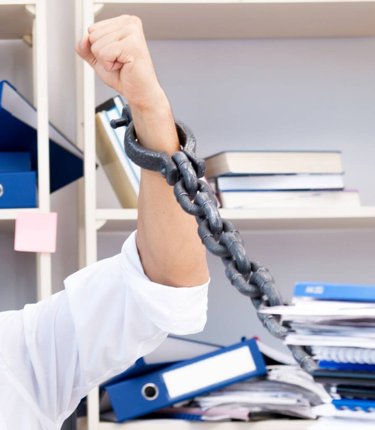 The employee attached and chained to his desk with chain - Фото, зображення