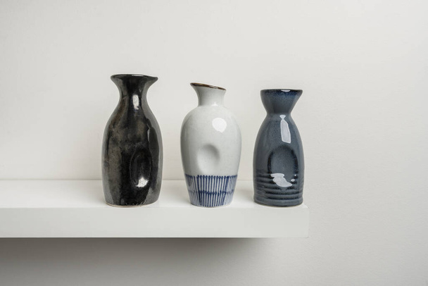 Pequenos vasos decorativos de porcelana de várias cores em uma prateleira de madeira branca - Foto, Imagem