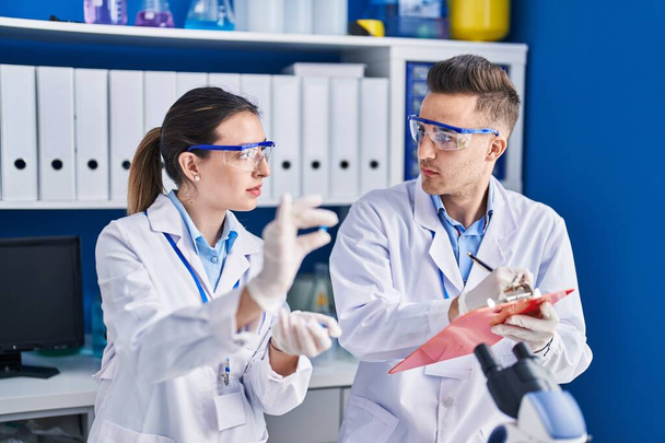 Mies ja nainen tutkijat tilalla pillereitä kirjoittaa asiakirjaan laboratoriossa - Valokuva, kuva