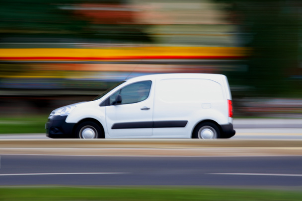 Быстрый белый минивэн едет по дороге
 - Фото, изображение