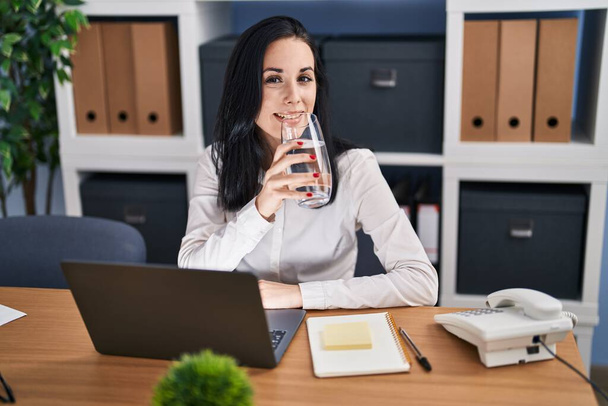 Jovem mulher caucasiana empresária usando laptop beber copo de água no escritório - Foto, Imagem