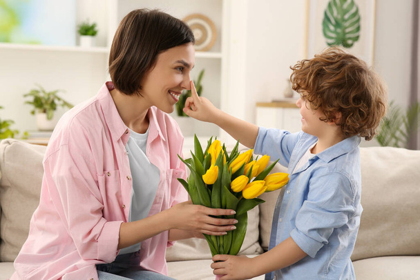 Happy woman with her cute son and bouquet of beautiful flowers at home. Mother's day celebration - Foto, immagini